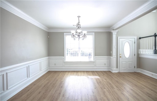 foyer with light hardwood / wood-style flooring, ornamental molding, and a chandelier