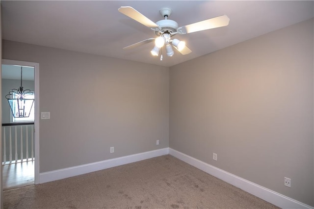 spare room featuring ceiling fan with notable chandelier