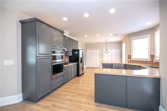 kitchen with kitchen peninsula, appliances with stainless steel finishes, sink, backsplash, and gray cabinetry