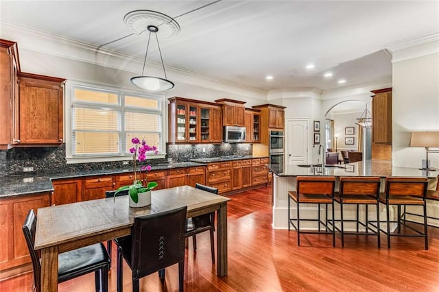 1109 Pine Grove Ave NE, Brookhaven, GA 30319 - kitchen featuring stainless steel appliances, brown cabinets, a kitchen breakfast bar, dark wood finished floors, and backsplash