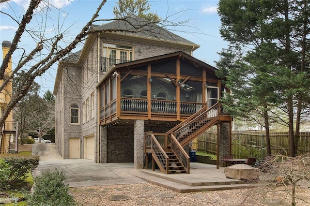 1109 Pine Grove Ave NE, Brookhaven, GA 30319 - back of house featuring a sunroom, an attached garage, concrete driveway, fence, and stairs