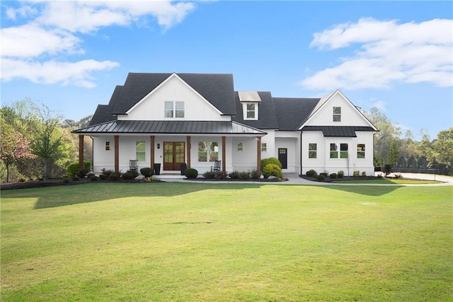 modern farmhouse featuring a standing seam roof, french doors, a porch, a front yard, and metal roof