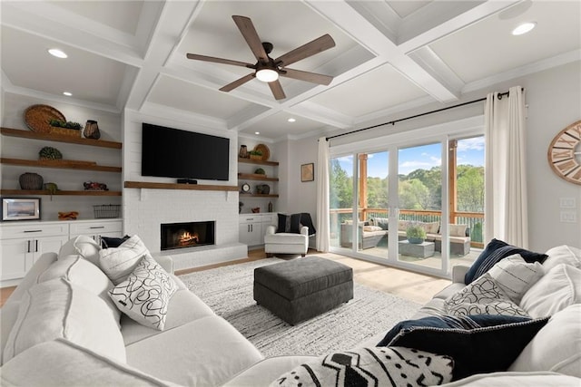 living room with built in shelves, ceiling fan, coffered ceiling, a brick fireplace, and beam ceiling