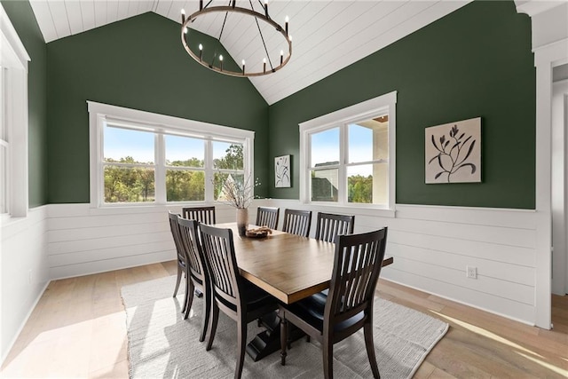 dining area featuring lofted ceiling, a wainscoted wall, a notable chandelier, and wood finished floors