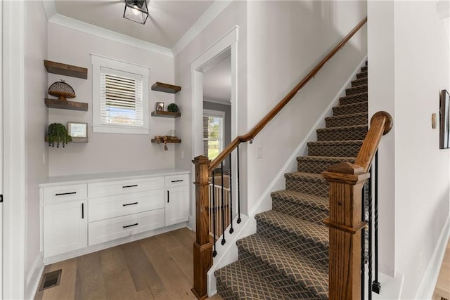 stairway featuring crown molding, wood finished floors, and visible vents