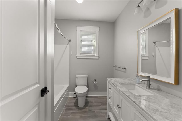 full bathroom featuring toilet, wood finished floors, vanity, shower / washtub combination, and baseboards