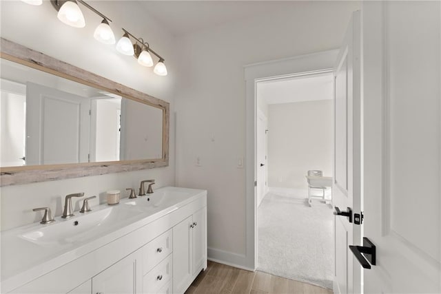 bathroom featuring baseboards, wood finished floors, a sink, and double vanity