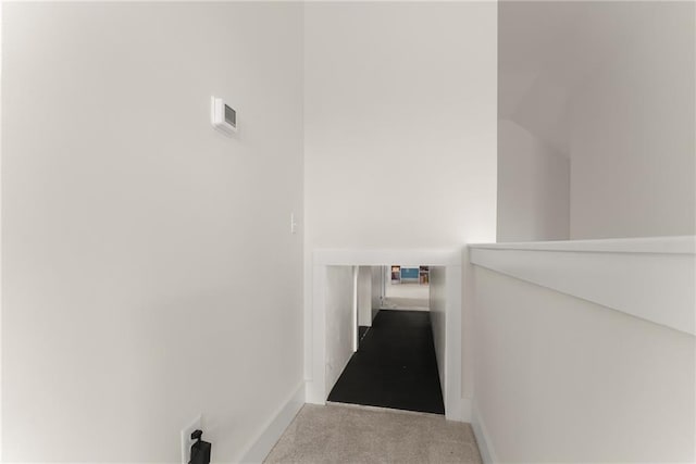hallway featuring carpet flooring, baseboards, and an upstairs landing