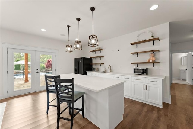 kitchen with open shelves, light countertops, a sink, dark wood-style flooring, and black fridge