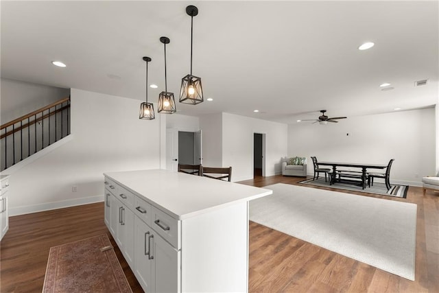 kitchen with visible vents, white cabinetry, a ceiling fan, a kitchen island, and hanging light fixtures
