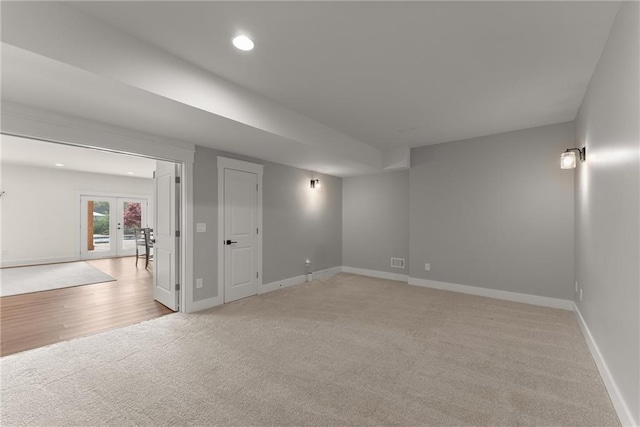 basement featuring recessed lighting, french doors, baseboards, light wood-style flooring, and light colored carpet