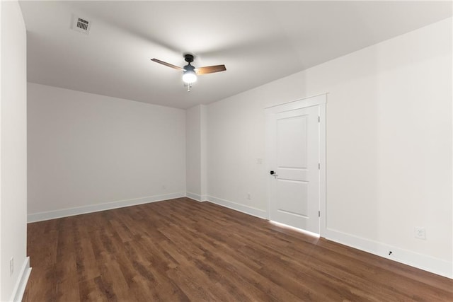 empty room featuring ceiling fan, baseboards, visible vents, and dark wood-style floors