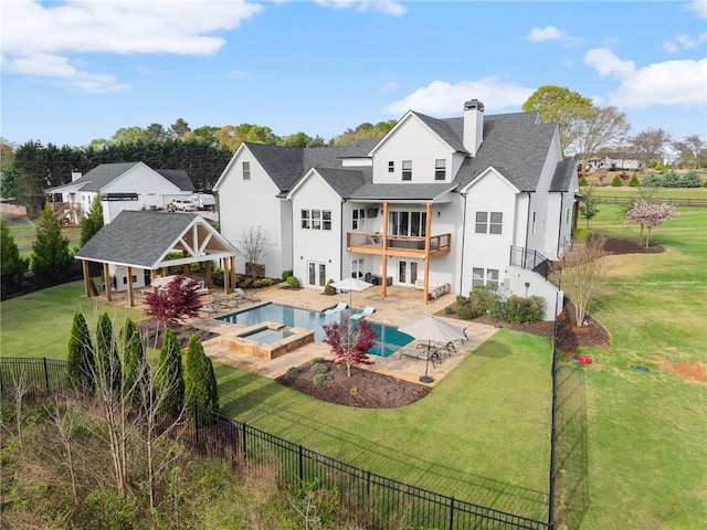 back of property with a fenced backyard, a chimney, a patio area, a balcony, and a yard