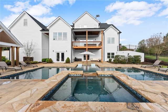 view of pool featuring fence, french doors, a pool with connected hot tub, and a patio