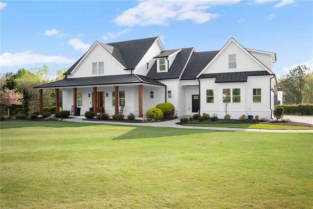 modern farmhouse with a standing seam roof, a front yard, covered porch, and metal roof
