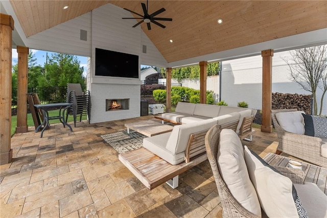 view of patio / terrace with fence, an outdoor living space with a fireplace, and ceiling fan