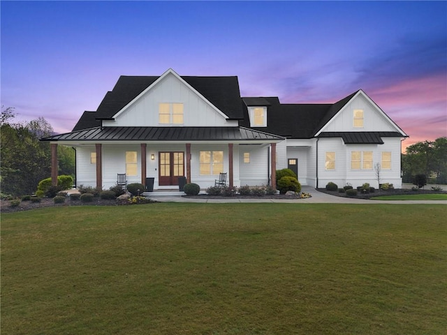 modern farmhouse style home featuring a lawn, board and batten siding, covered porch, metal roof, and a standing seam roof