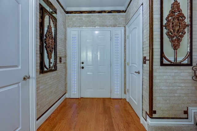 entryway featuring light wood-type flooring, crown molding, and brick wall