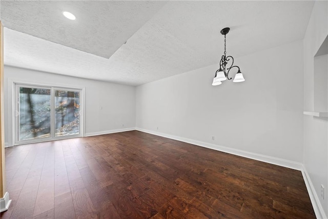 empty room with a chandelier, wood-type flooring, and a textured ceiling