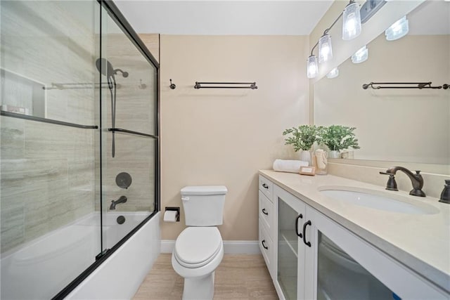 full bathroom with vanity, bath / shower combo with glass door, and toilet