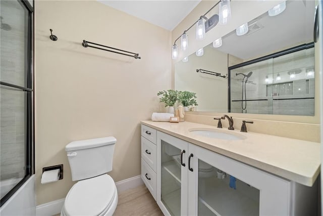 full bathroom with vanity, bath / shower combo with glass door, and toilet