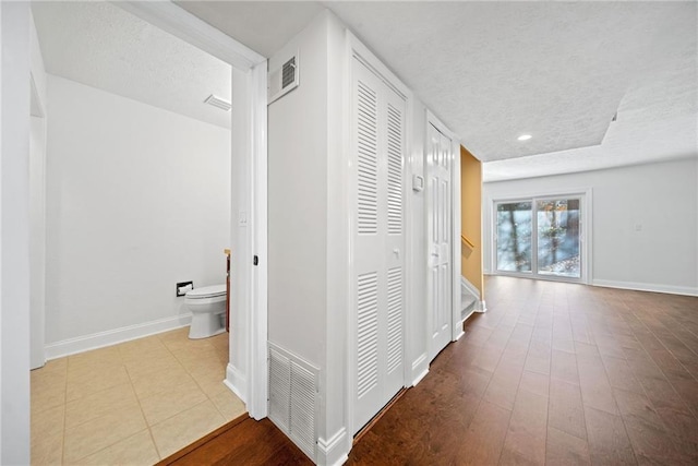 hall with light wood-type flooring and a textured ceiling