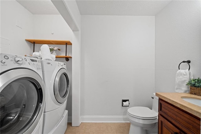 laundry area with independent washer and dryer, a textured ceiling, and light tile patterned flooring