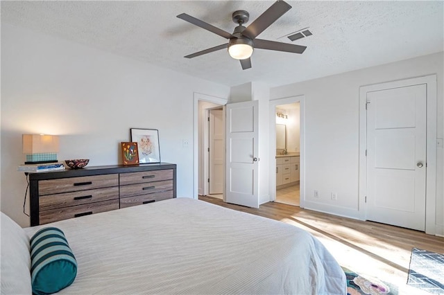 bedroom featuring connected bathroom, a textured ceiling, ceiling fan, and light hardwood / wood-style flooring