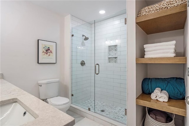 bathroom with toilet, vanity, and a shower with shower door