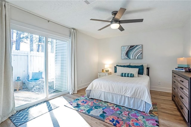 bedroom with access to exterior, ceiling fan, a textured ceiling, and light hardwood / wood-style flooring