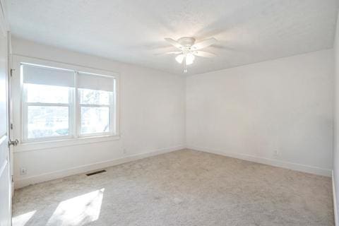 empty room with ceiling fan and light colored carpet