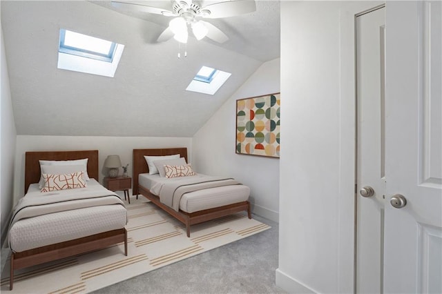 bedroom featuring ceiling fan, lofted ceiling with skylight, and carpet