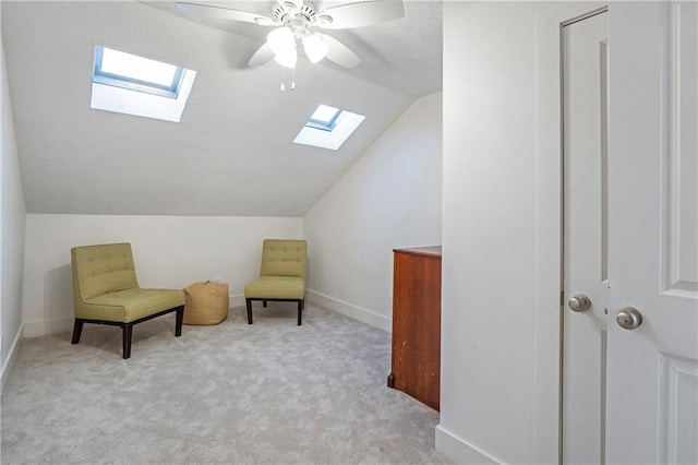 sitting room with light carpet, lofted ceiling with skylight, and ceiling fan