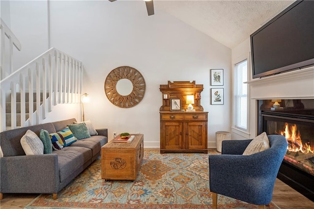 living room featuring a textured ceiling, ceiling fan, light wood-type flooring, and vaulted ceiling