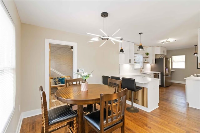 dining area featuring an inviting chandelier, sink, and light wood-type flooring