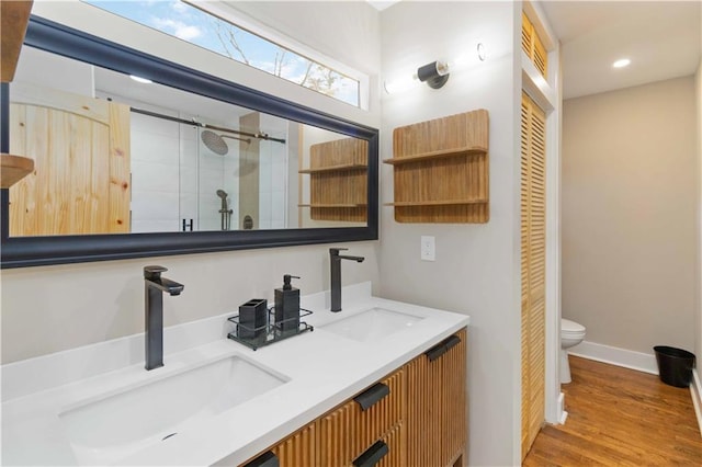 bathroom featuring hardwood / wood-style flooring, vanity, toilet, and a shower with door