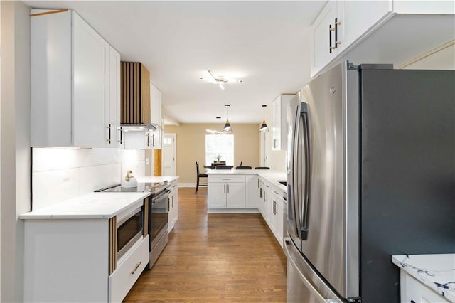 kitchen featuring hardwood / wood-style flooring, appliances with stainless steel finishes, white cabinetry, decorative backsplash, and decorative light fixtures