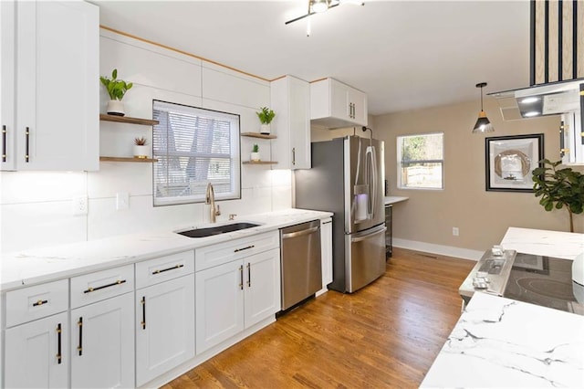 kitchen with decorative light fixtures, sink, white cabinets, stainless steel appliances, and light stone countertops