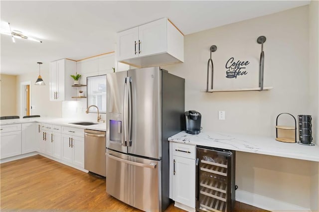 kitchen featuring wine cooler, appliances with stainless steel finishes, sink, and white cabinets