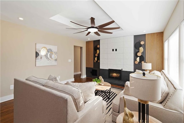 living room with dark wood-type flooring, ceiling fan, and a tile fireplace