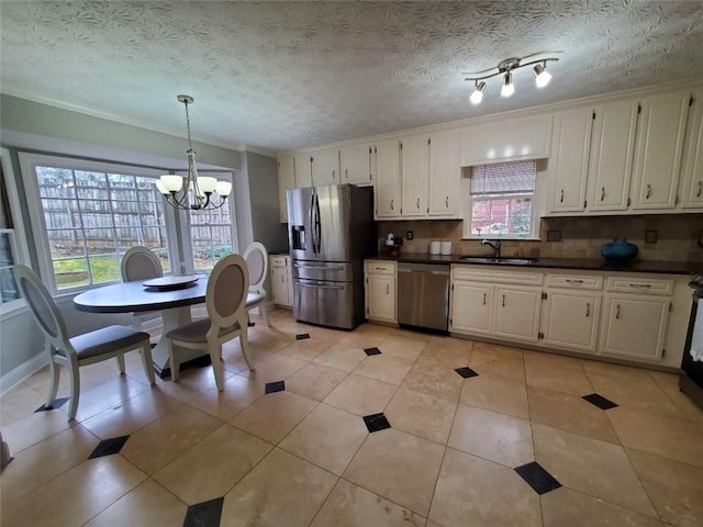 kitchen with appliances with stainless steel finishes, dark countertops, a chandelier, and plenty of natural light