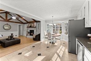 kitchen featuring lofted ceiling, tile patterned flooring, a fireplace, white cabinetry, and appliances with stainless steel finishes