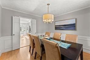 dining space featuring ornamental molding, a wainscoted wall, and wood finished floors