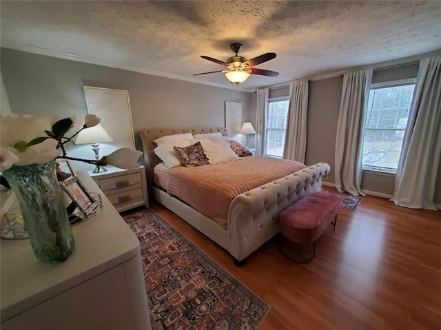 bedroom with ceiling fan, crown molding, a textured ceiling, and wood finished floors