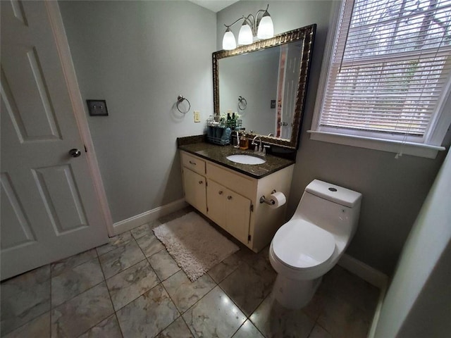 half bath with baseboards, vanity, and toilet