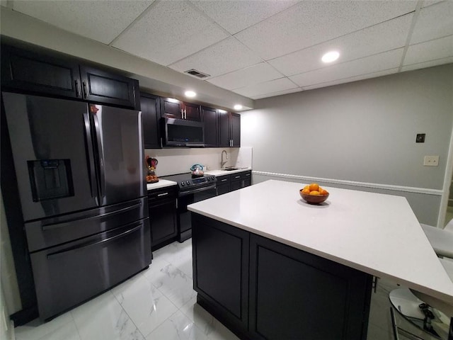 kitchen featuring visible vents, marble finish floor, light countertops, a center island, and black appliances