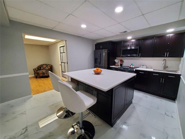 kitchen featuring appliances with stainless steel finishes, marble finish floor, visible vents, and a kitchen bar