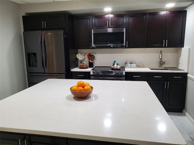 kitchen with stainless steel appliances, marble finish floor, light countertops, and a kitchen island