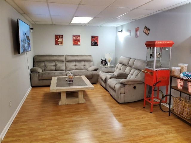 living area featuring a drop ceiling, baseboards, and wood finished floors