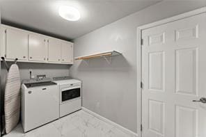 clothes washing area featuring washing machine and dryer, marble finish floor, cabinet space, and baseboards